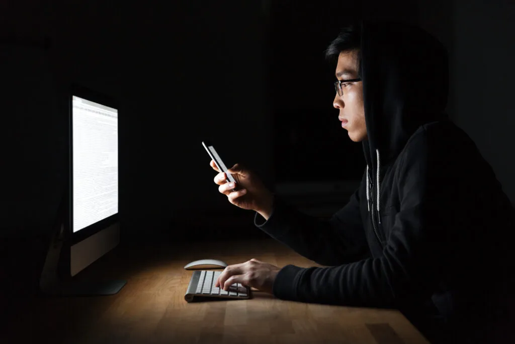 hacker-using-laptop-and-mobile-phone-in-dark-room
