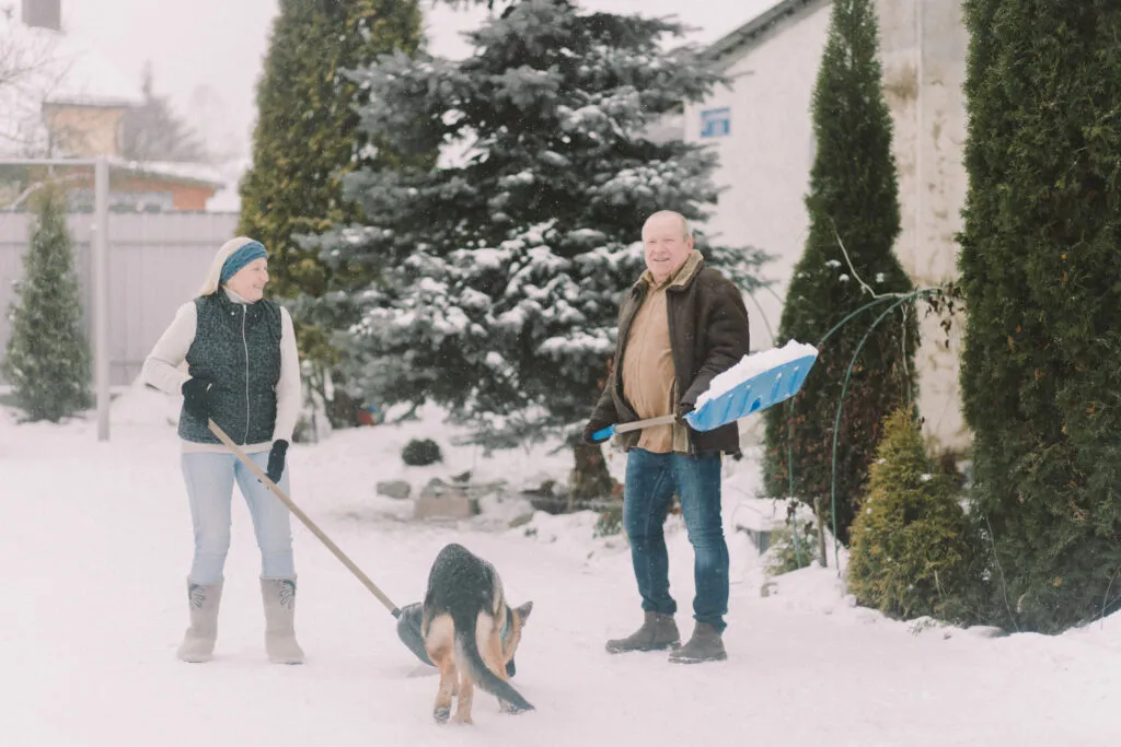 Couple shoveling snow with dog